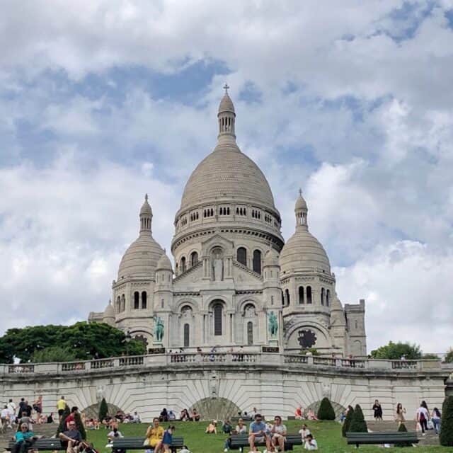 Sacré-Cœur - Large Marble Church with three domes and people enjoying the grass in front of the building