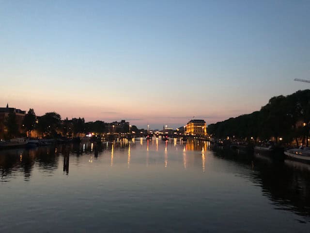 View of the Amstel River at Sunset with the canal houses of Amsterdam on either side of the water