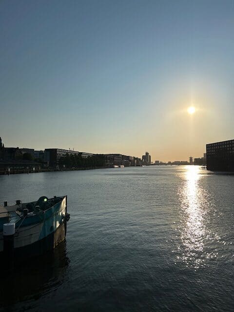 Sunset over water with modern buildings and a boat