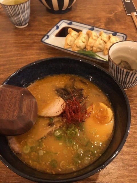 Bowl of Ramen soup shown with dumplings