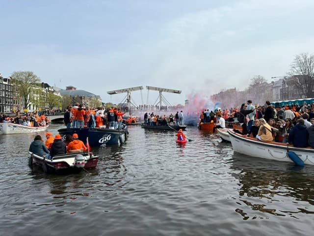 Boats on a Canal in City Center Amsterdam on Kings day with everyone in orange