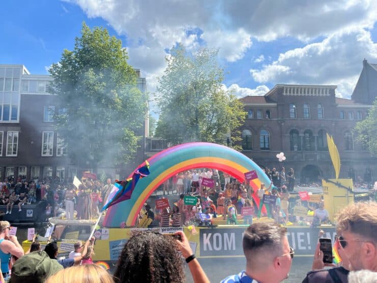 Gay Pride Amsterdam 2024 Floats down the main canal with canal houses behind a giant inflatable rainbow