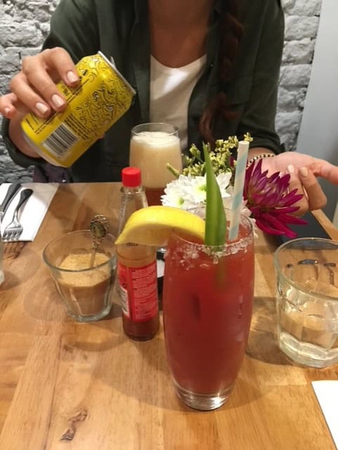 Restaurant Table showing a bloody mary and someone pouring a beer out of a yellow can 