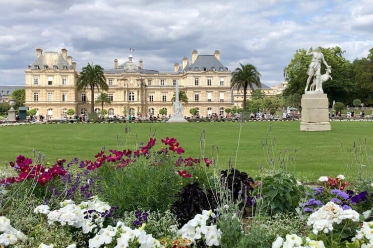Luxembourg Gardens in Paris with colorful flowers, large green grass and a palace in the background
