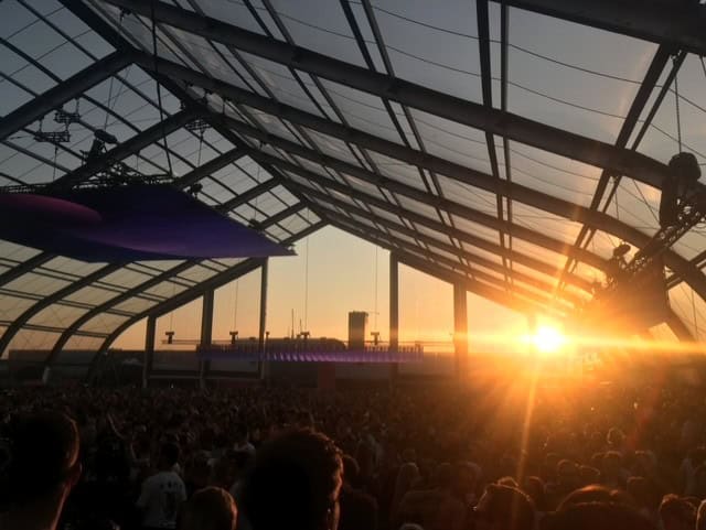 Sunsets over NSDM Concert Venue with people dancing under a canopy