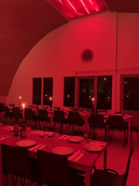 Red lit empty dining room with candles and  black chairs