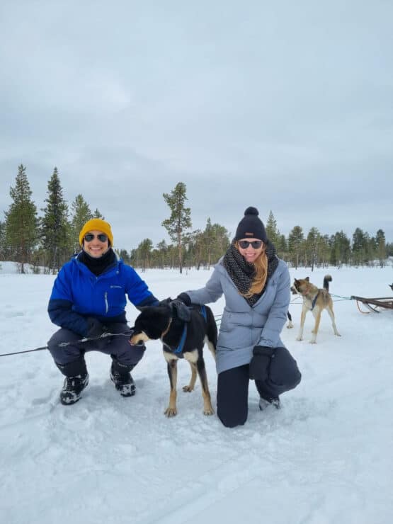 man and women in winter coats smiling with husky dog