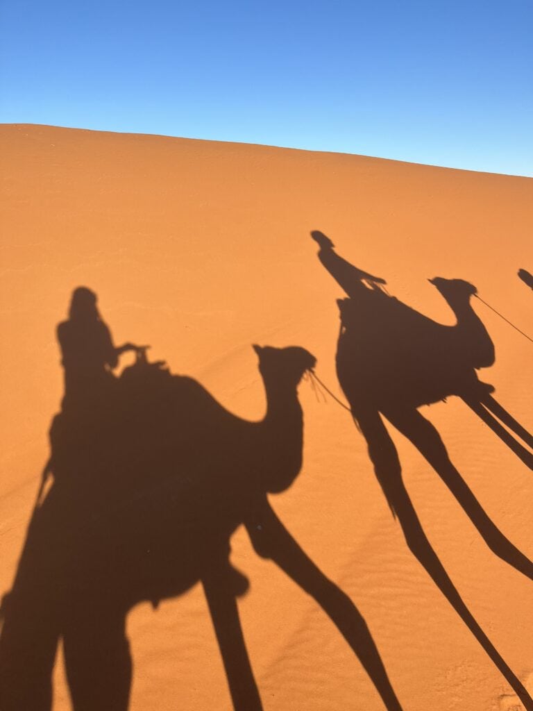 two shadows of people riding camels in the Moroccan Desert 